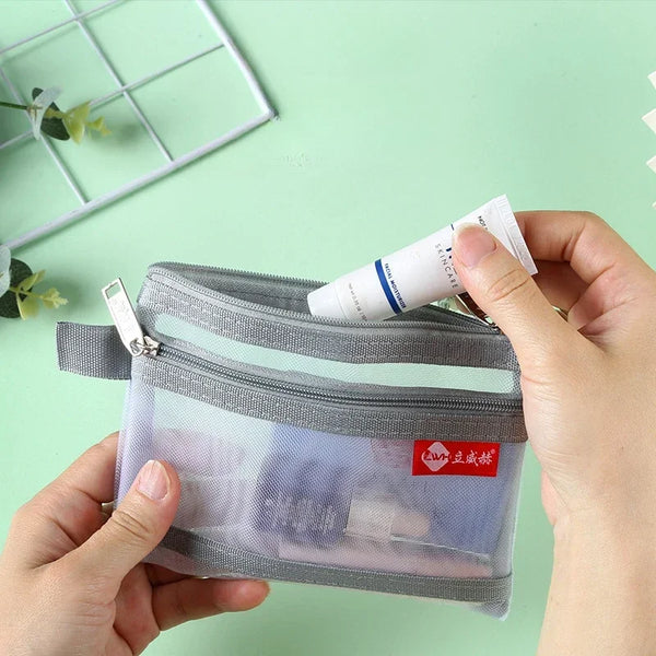 A hand holds a clear double-layer zipper pouch with a gray exterior, used for storing coins and cards.