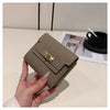 A hand holds a beige multi-slot card holder with gold accents on a white surface.