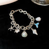 Silver charm bracelet featuring an ocean pearl, starfish, and seashell accents.