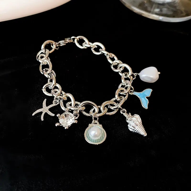 Silver charm bracelet featuring an ocean pearl, starfish, and seashell accents.