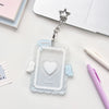 Clear acrylic photocard holder with a heart design and angel wings attached to a silver charm