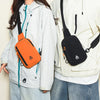 A person is wearing a bright orange nylon sling crossbody bag on their chest while holding a white jacket.