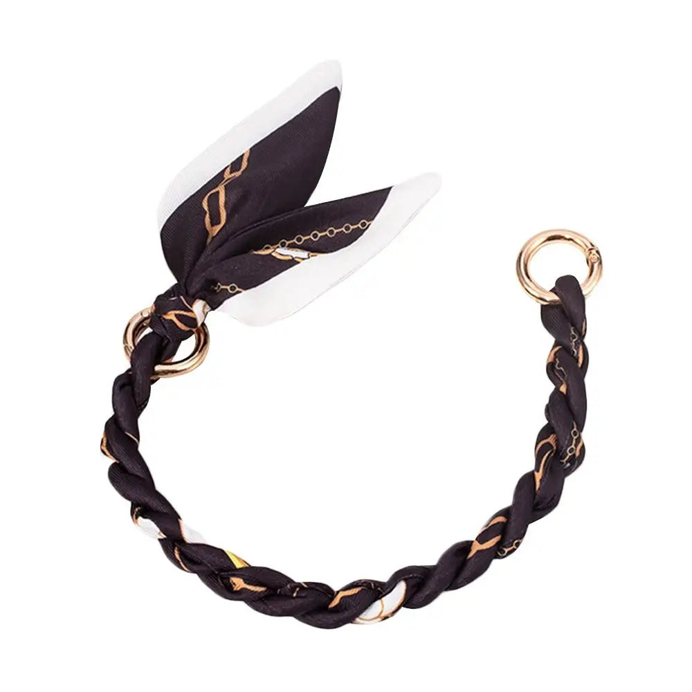 Schwarz-weißes geflochtenes Seidenschal-Taschenketten mit goldfarbenen Ringen.