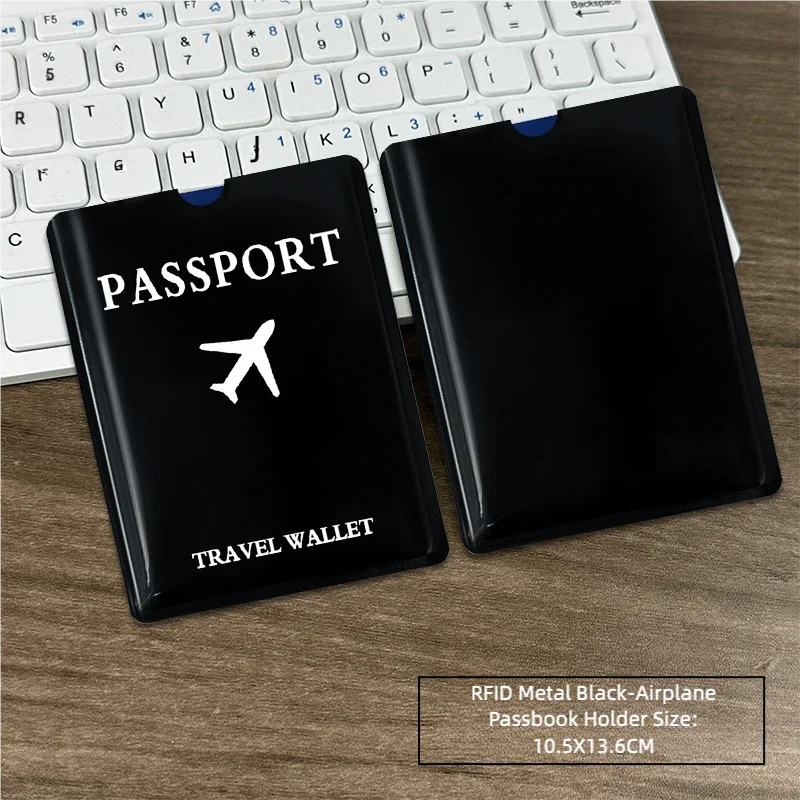 Black RFID metal passport holder with an airplane design placed on a wooden desk next to a laptop keyboard.