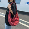 A person is holding a red corduroy casual crossbody shoulder bag against a white wall.