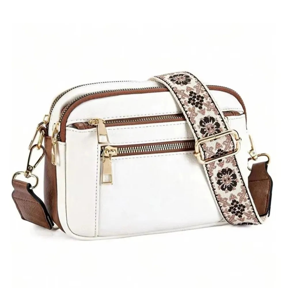 A white and brown patterned PU leather crossbody bag with gold hardware.