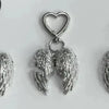 Silver metal angel wing keychain charm with a heart loop.