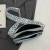 A light blue patterned vegan PU crossbody bag with a gold chain strap resting on a gray blazer.