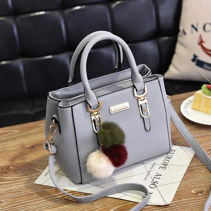 A light gray vintage PU leather tassel handbag resting on a wooden surface.
