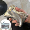 A hand holds a silver metallic leather compact coin purse and key holder with a textured finish.