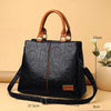 Sac bandoulière en cuir PU noir avec anses et sangle en cuir marron, présenté sur fond beige.