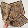 An elegant paisley silk hair scarf and headband featuring intricate brown, beige, and cream patterns.