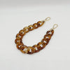 A close-up of a gold-toned, multi-link acrylic chain bracelet with a clasp.