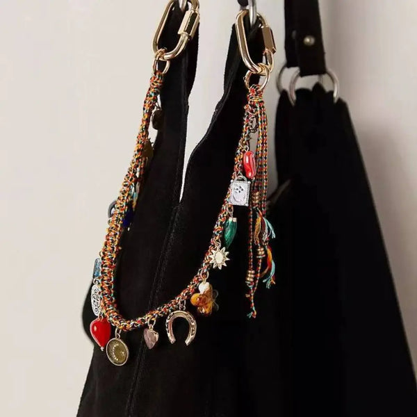 A necklace with various charms and beads on a gold-toned lanyard hanging against a black background.
