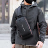 A person wearing a black waterproof jacket is holding an anti-theft crossbody chest bag.