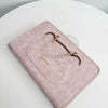 A pink leather laptop sleeve with a rounded cutout and brown leather and white beaded straps.