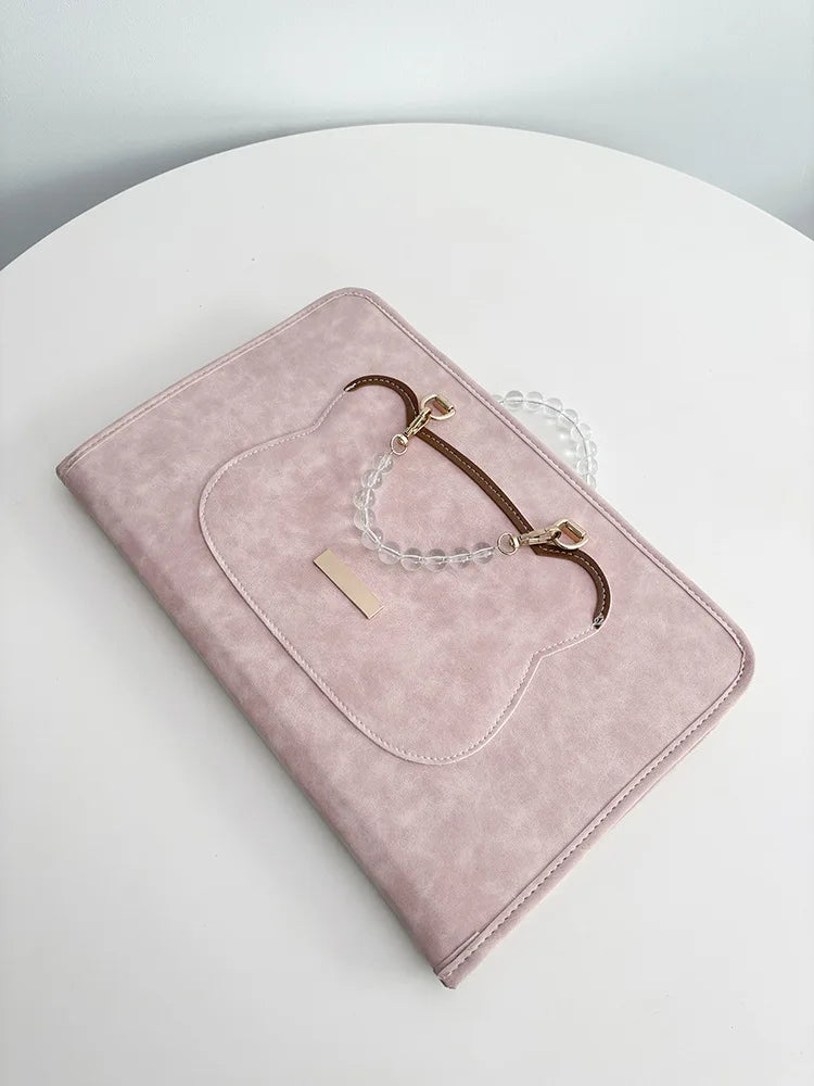 A pink leather laptop sleeve with a rounded cutout and brown leather and white beaded straps.