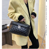 A woman wearing a beige blazer holds a black quilted makeup storage pouch.