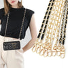 A black leather crossbody purse with gold chain straps is displayed next to a long strand of matching chains.