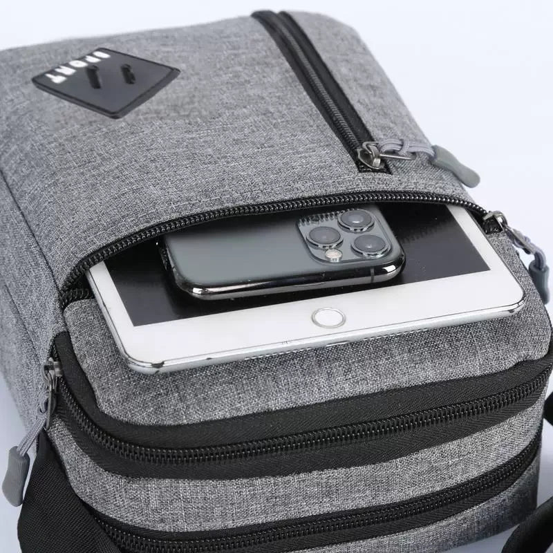 A gray lightweight crossbody sling bag with a black zipper and a smartphone visible inside.