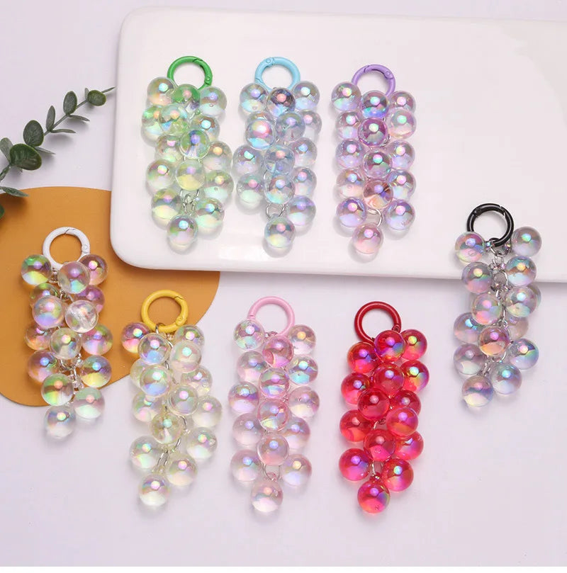 Colección de llaveros de uva acrílica en varios tonos de verde, azul, púrpura y rosa.
