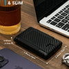 A black slim aluminum wallet is shown next to a laptop and a smartphone on a wooden surface.