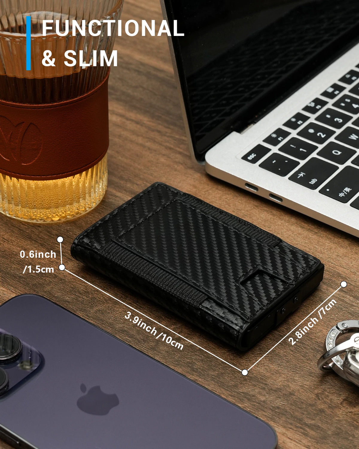 A black slim aluminum wallet is shown next to a laptop and a smartphone on a wooden surface.
