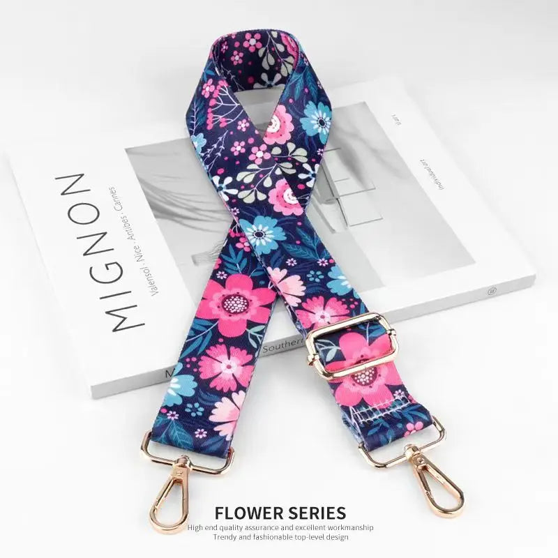 A floral patterned nylon bag strap in blue and pink is displayed on a white box.