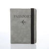 A gray passport organizer with a black strap and a stylized airplane icon on the cover.
