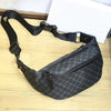 Sac à la taille noire, bandoulière, avec fermeture éclair et sangle noire, posé sur une surface en bois.