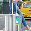 A person is holding a silver suitcase with a visible luggage tag and steel ring in front of a yellow vehicle.