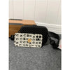 A white and black striped PU leather shoulder bag resting on a gray surface next to a wooden box.