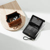 A black PU leather mini wallet with a pendant is shown open on a light wooden surface.