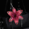 A realistic pink orchid flower keychain attached to a black leather bag.