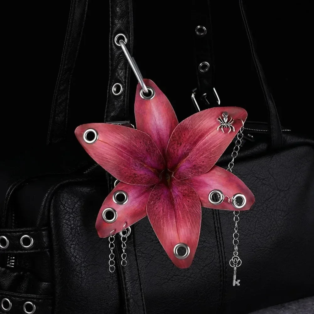 A realistic pink orchid flower keychain attached to a black leather bag.