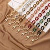 A collection of colorful acrylic handbag strap chains laid out on a brown fabric.
