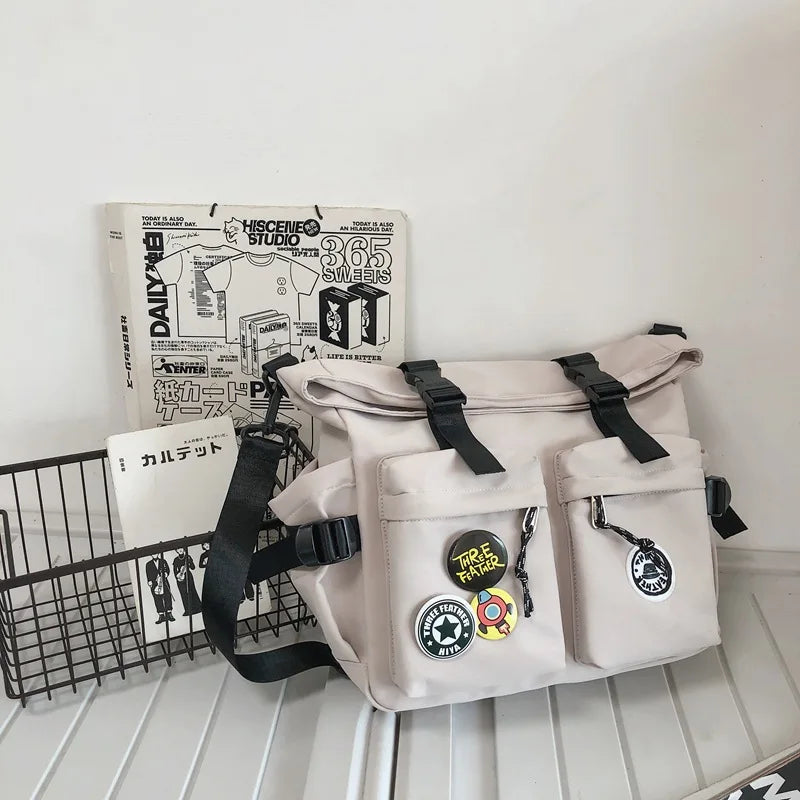 A light beige nylon crossbody bag with multiple pockets and straps is displayed next to a sign.