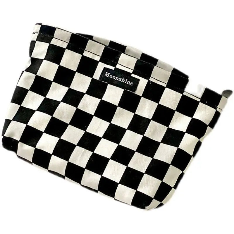 A black and white checkered cosmetic storage bag with the word Moonshine printed on it.