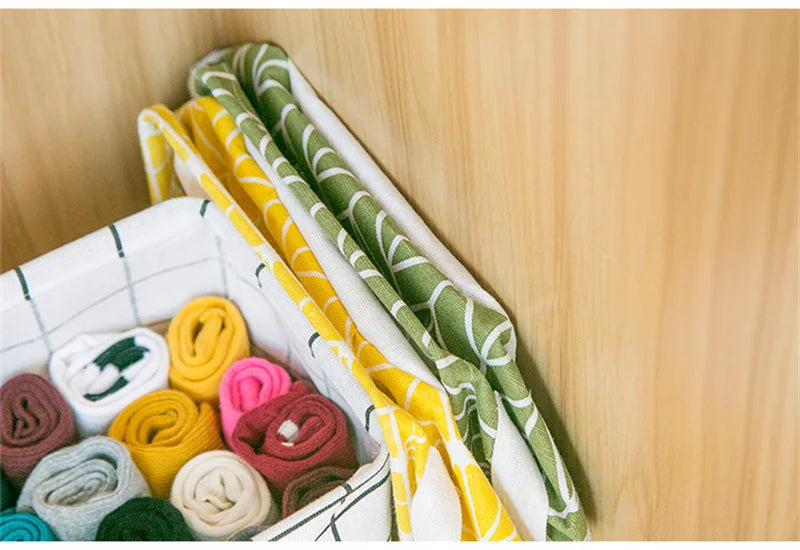 A woven storage basket filled with colorful rolled fabric bundles in yellow, green, pink, and yellow-striped linen.
