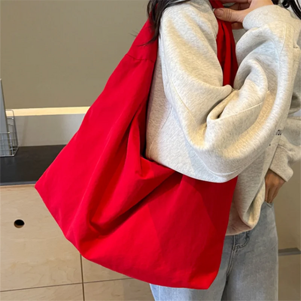 Eine Frau hält eine leuchtend rote, strapazierfähige Nylon-Tasche an ihrer Brust.