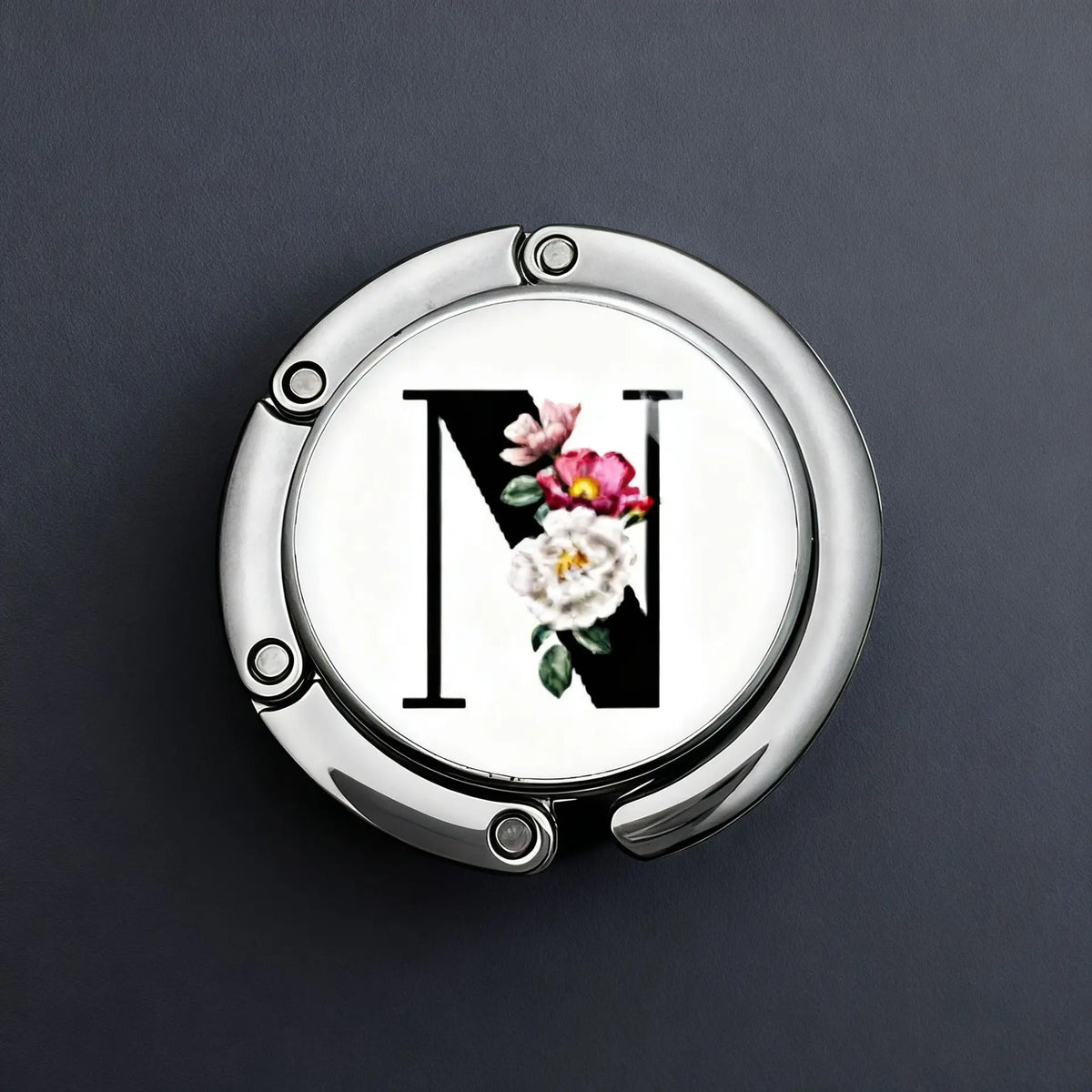 A silver metal fold-over letter hanger hook with a decorative floral design on the surface.