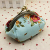A light blue canvas coin purse with a vintage rose print fabric and a gold-toned metal clasp.