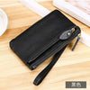Black genuine leather wristlet clutch wallet with zipper closure resting on a wooden surface.