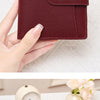 A close-up of a brown leather RFID-blocking compact bifold wallet being held open to show the interior.