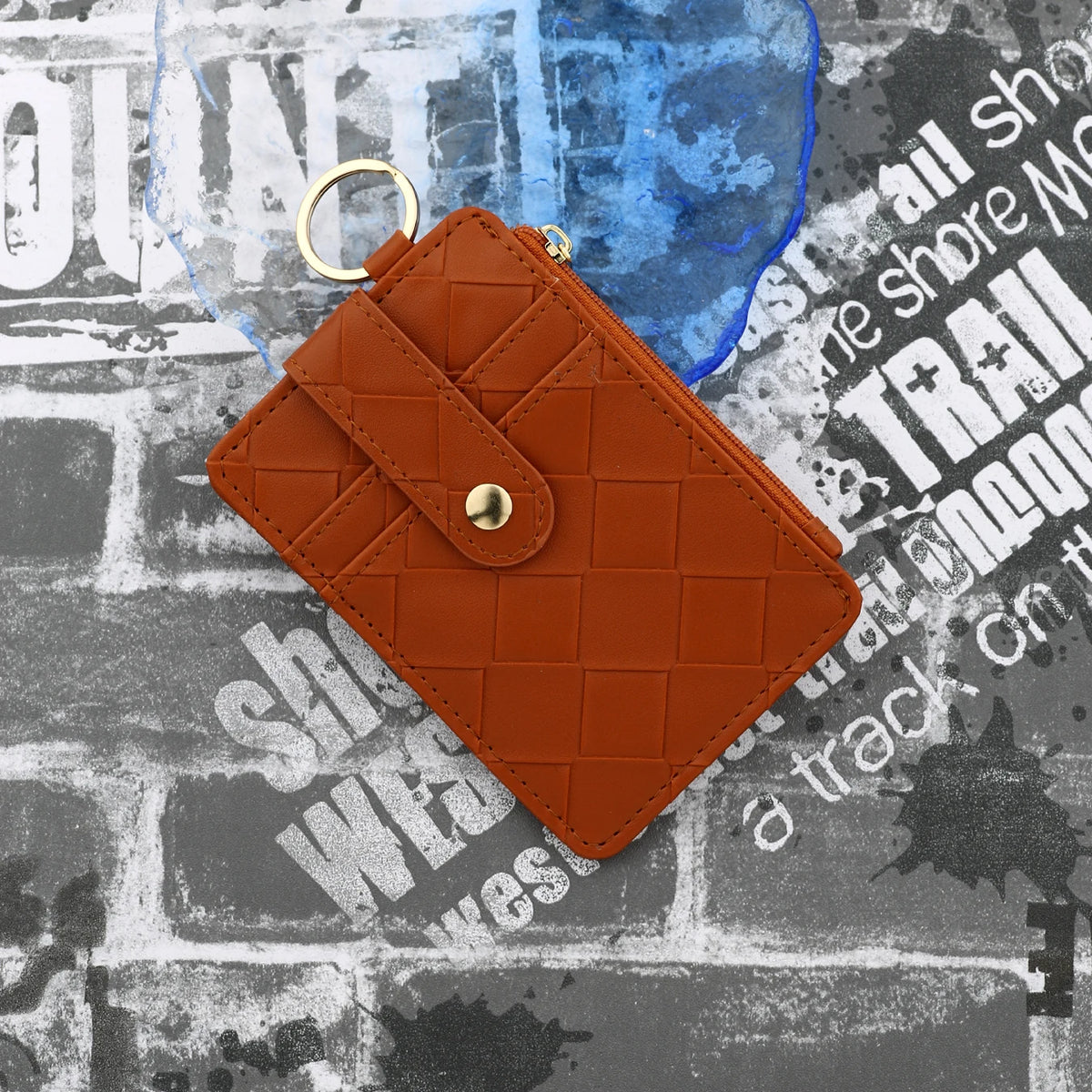 A brown PU leather card holder wallet with a quilted design is shown against a textured gray background.