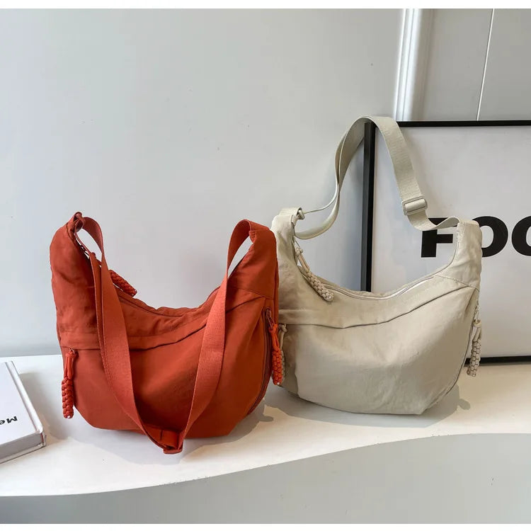 Tan Nylon-Crossbody-Tasche in verbranntem Orange auf weißer Oberfläche.
