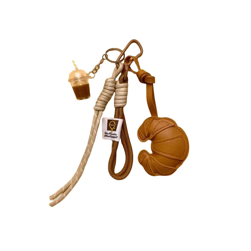A leather croissant-shaped keychain with a lanyard and pendant.