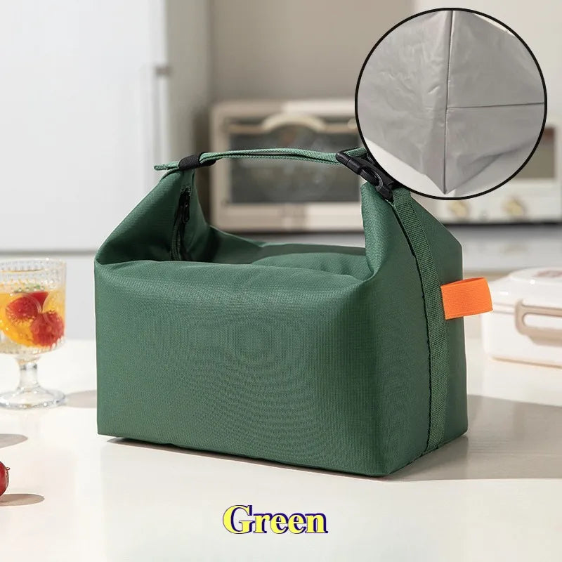 Une sacoche de lunch isotherme vert foncé avec une fenêtre circulaire transparente est montrée sur une surface blanche.