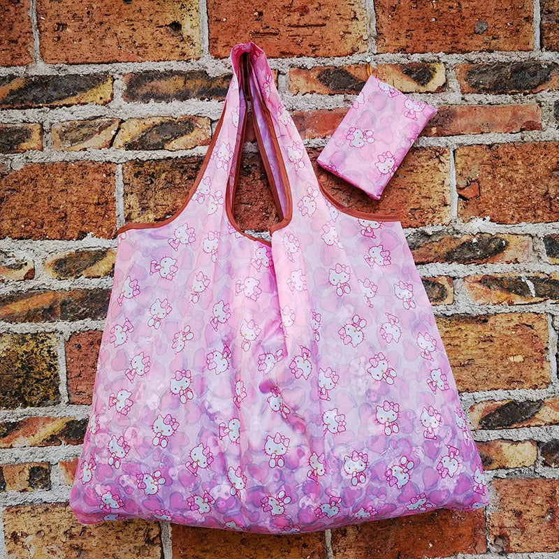 A pink reusable shopping bag is displayed against a brick wall.