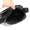 A hand is opening a black vintage leather messenger bag to show the interior.